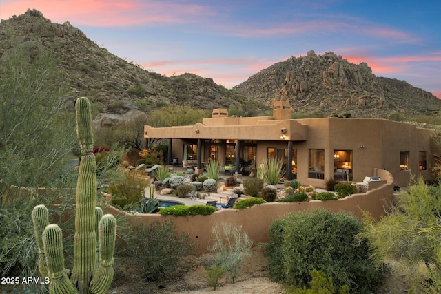 back of property at dusk featuring a mountain view and a patio area