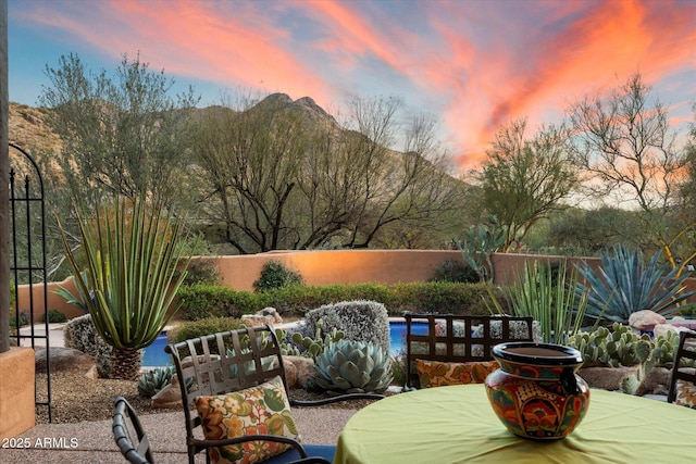 patio terrace at dusk featuring a mountain view and fence