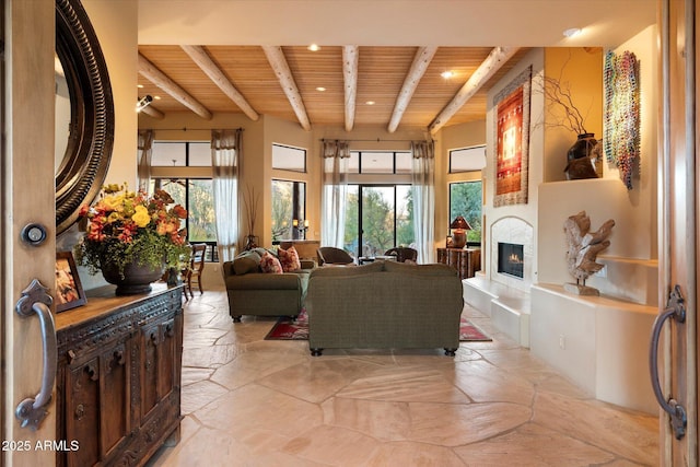 living area with beamed ceiling, stone tile flooring, recessed lighting, a large fireplace, and wood ceiling