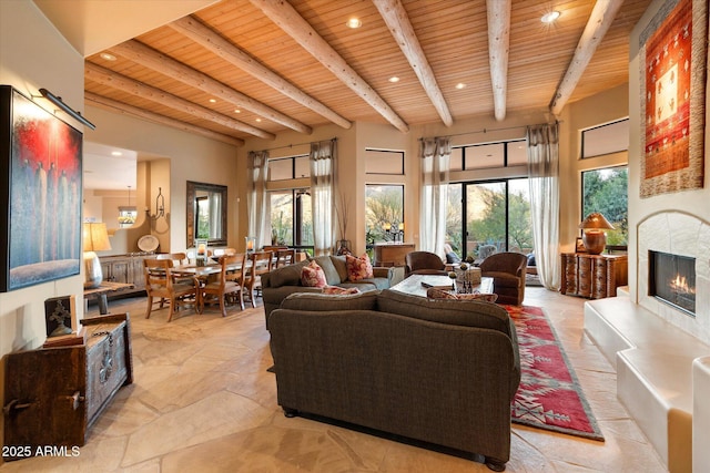 living area featuring recessed lighting, beamed ceiling, wood ceiling, and a warm lit fireplace