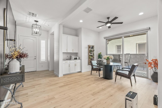 dining room featuring ceiling fan with notable chandelier and light hardwood / wood-style flooring