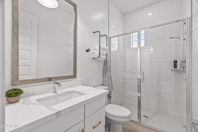 bathroom with toilet, hardwood / wood-style floors, vanity, and walk in shower