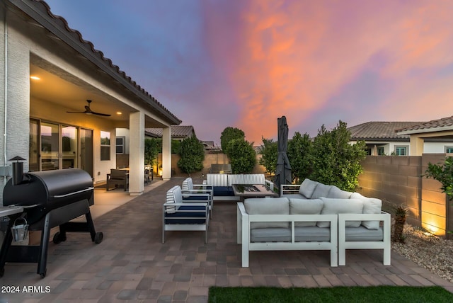 patio terrace at dusk featuring grilling area, ceiling fan, and an outdoor living space with a fire pit