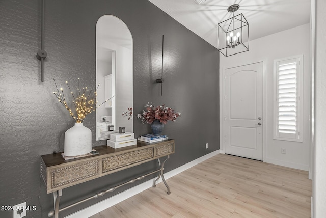 foyer with a chandelier, lofted ceiling, and light hardwood / wood-style flooring