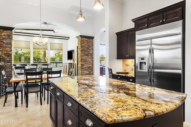 kitchen with decorative backsplash, ceiling fan with notable chandelier, a center island, built in refrigerator, and hanging light fixtures