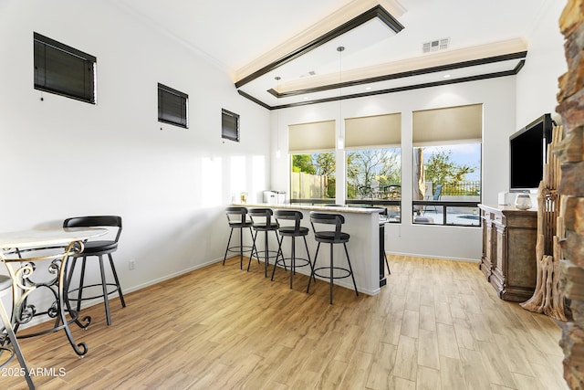 kitchen featuring a breakfast bar, light wood-type flooring, kitchen peninsula, and ornamental molding