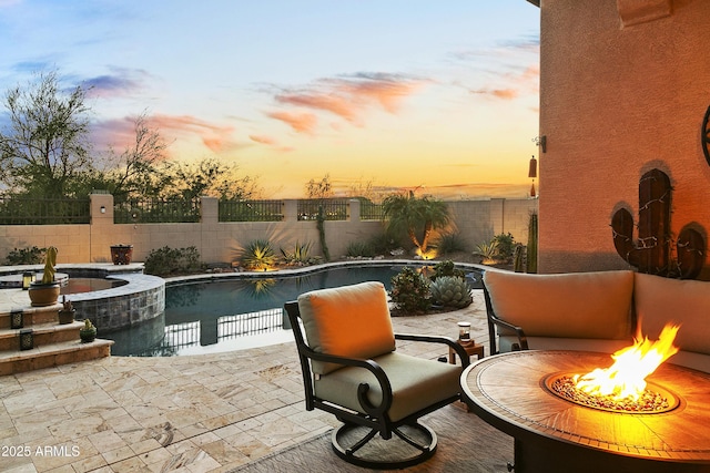 pool at dusk with a fire pit and a patio