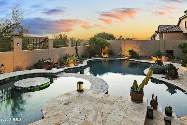 pool at dusk with a hot tub and a patio area