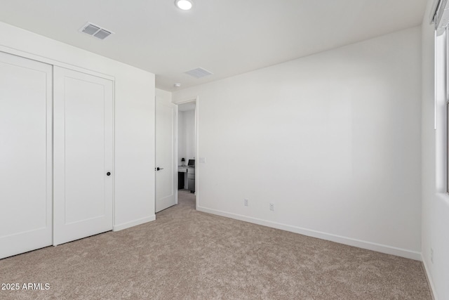 unfurnished bedroom featuring light colored carpet and a closet