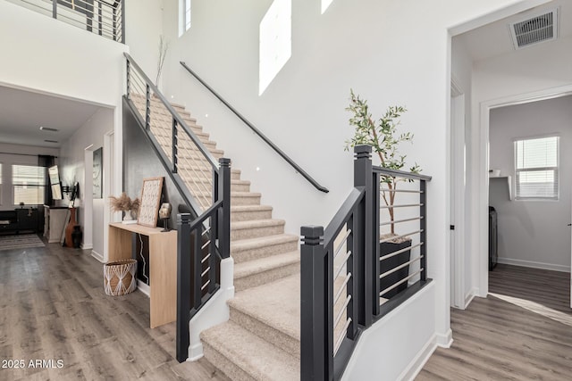 staircase featuring hardwood / wood-style floors, a high ceiling, and plenty of natural light