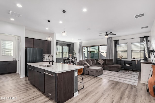 kitchen with pendant lighting, an island with sink, dark brown cabinets, and sink