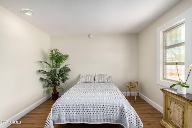 bedroom with multiple windows and dark hardwood / wood-style flooring