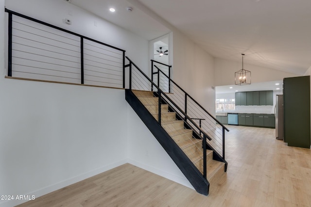 stairway featuring ceiling fan with notable chandelier, vaulted ceiling, and hardwood / wood-style flooring