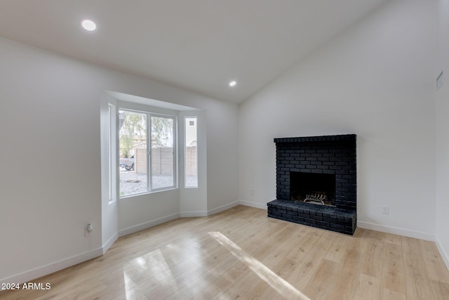 unfurnished living room with a fireplace, light hardwood / wood-style floors, and vaulted ceiling