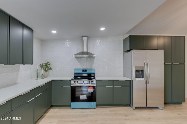 kitchen with decorative backsplash, stainless steel appliances, light hardwood / wood-style flooring, and wall chimney range hood