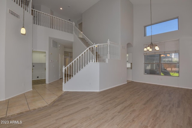 unfurnished living room featuring a high ceiling, wood-type flooring, and a notable chandelier