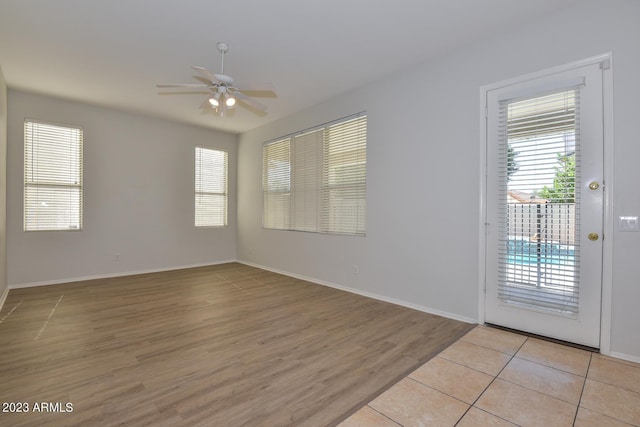 empty room with ceiling fan and light hardwood / wood-style flooring