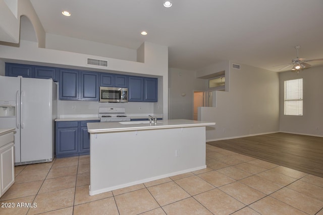 kitchen with light tile patterned floors, white appliances, and blue cabinets