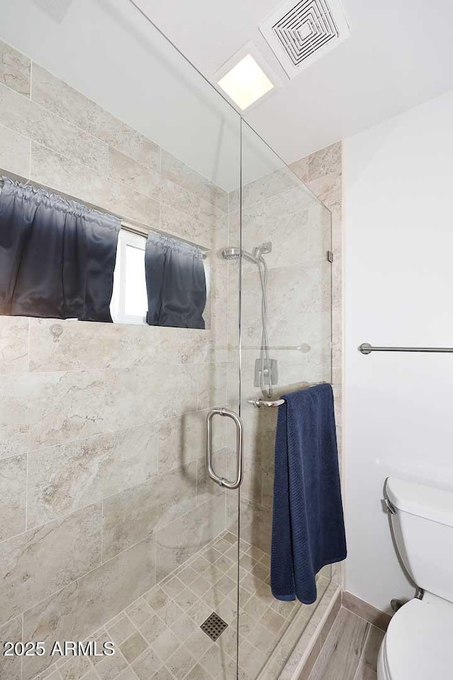 bathroom with a shower with door, hardwood / wood-style flooring, and toilet