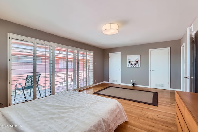 bedroom featuring visible vents, baseboards, wood finished floors, and access to outside