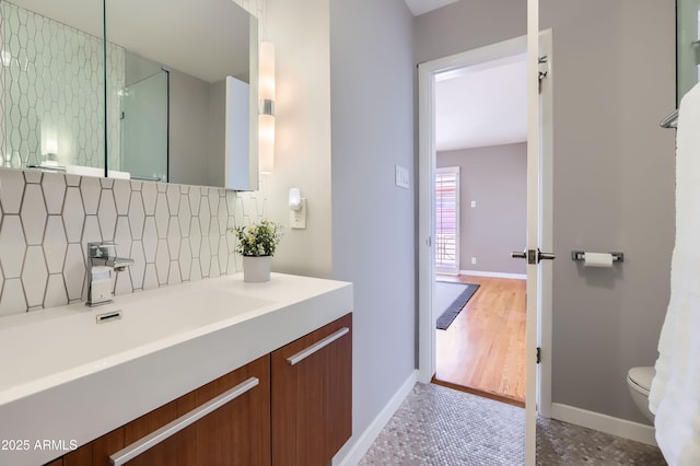 full bath with decorative backsplash, toilet, vanity, and baseboards