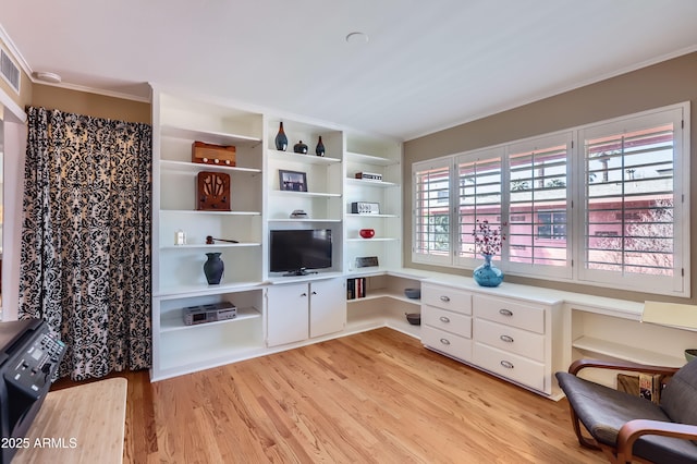 living area featuring crown molding, built in desk, and light wood finished floors