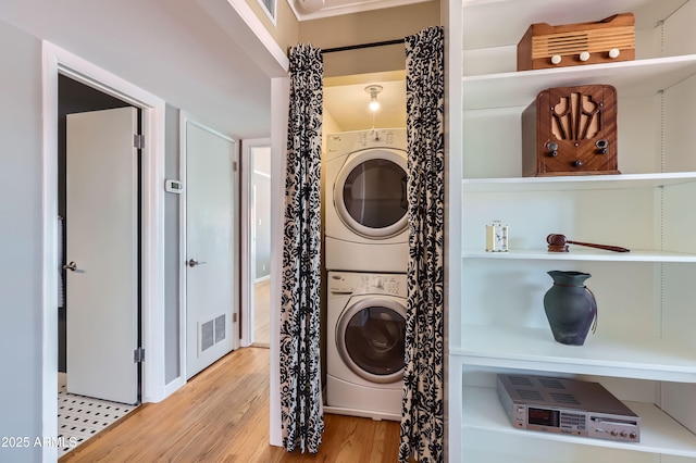 clothes washing area featuring visible vents, wood finished floors, laundry area, and stacked washer / dryer