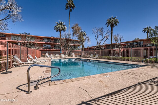 pool with a patio area and fence