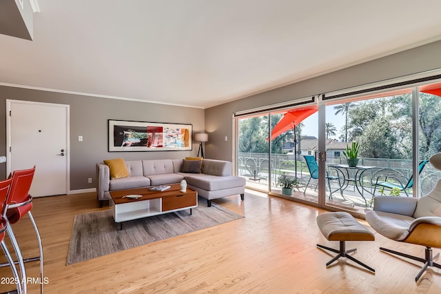 living area with crown molding, wood finished floors, and baseboards