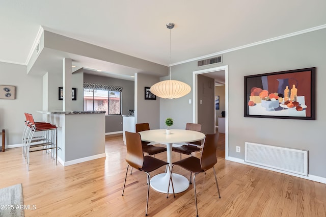 dining space featuring light wood-style floors, visible vents, and baseboards