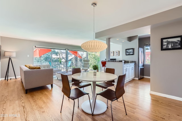 dining area with baseboards, light wood finished floors, and ornamental molding