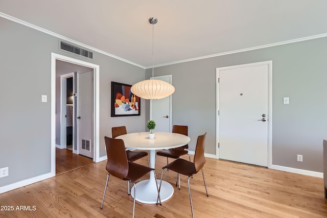 dining space featuring visible vents, baseboards, crown molding, and light wood-style floors