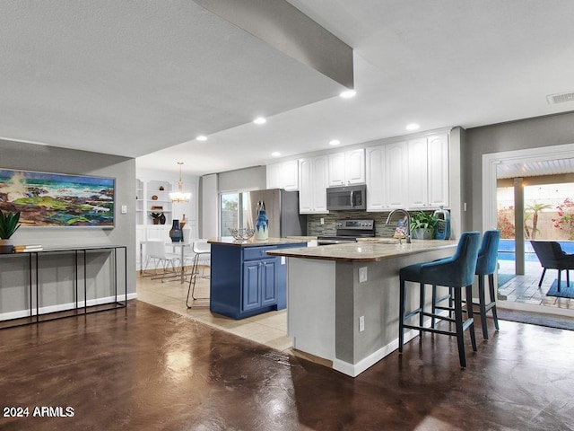 kitchen featuring kitchen peninsula, appliances with stainless steel finishes, blue cabinetry, white cabinets, and a breakfast bar area