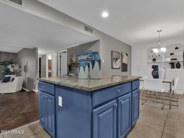 kitchen with blue cabinetry, light stone countertops, a center island, and decorative light fixtures