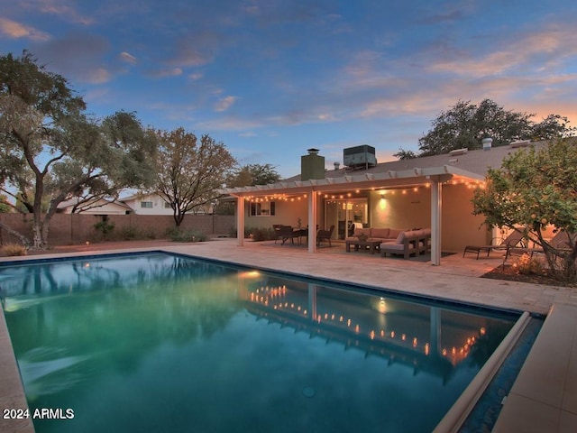 pool at dusk with an outdoor living space and a patio area