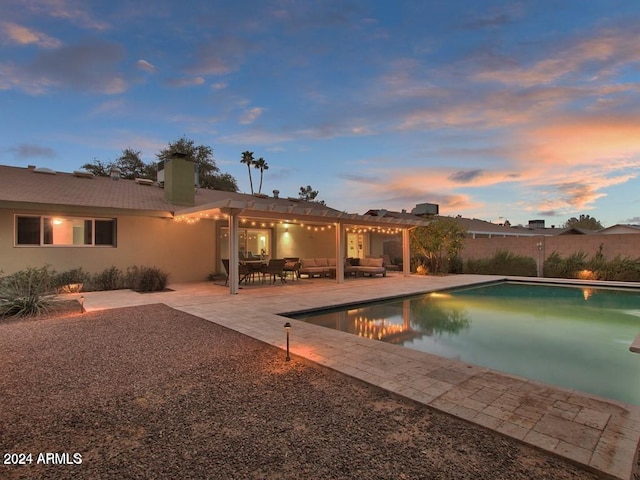 pool at dusk with outdoor lounge area and a patio area