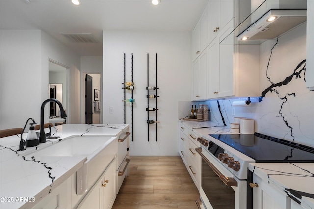 16533 E Dale Ln, Scottsdale, AZ 85262 - kitchen with white electric stove, light wood-type flooring, white cabinetry, light stone counters, and recessed lighting