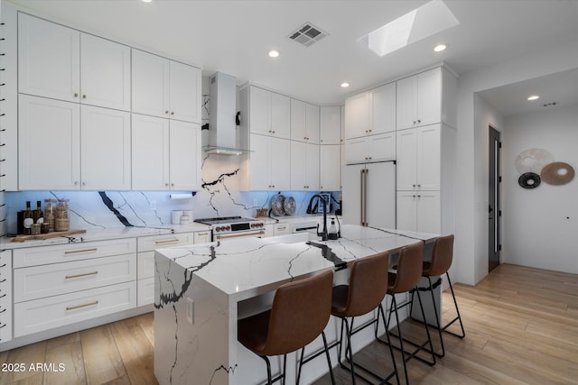 16533 E Dale Ln, Scottsdale, AZ 85262 - kitchen featuring premium appliances, wall chimney exhaust hood, a skylight, white cabinets, and recessed lighting