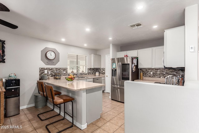 kitchen with visible vents, white cabinets, a peninsula, stainless steel appliances, and light countertops