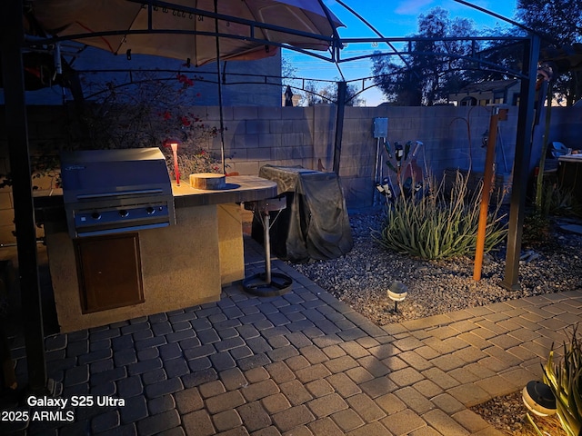 view of patio featuring exterior kitchen, a fenced backyard, and grilling area