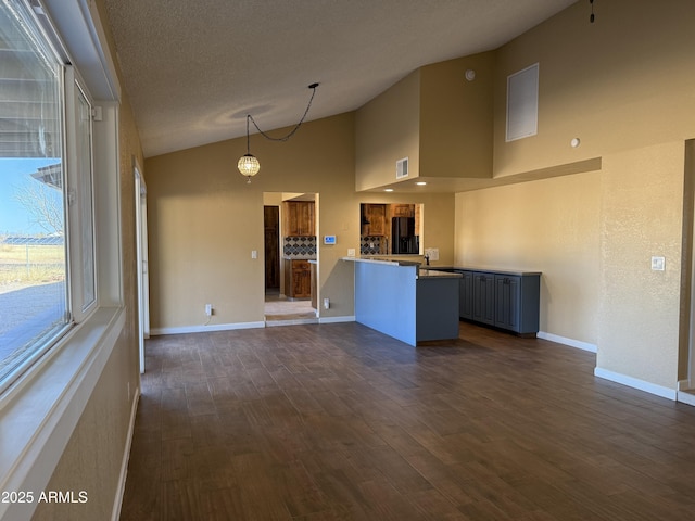 kitchen featuring black fridge with ice dispenser, a peninsula, dark wood-type flooring, and baseboards