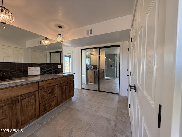 bathroom with double vanity, tasteful backsplash, visible vents, and a sink