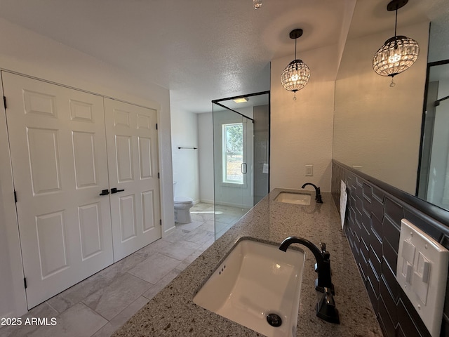 full bathroom with a sink, toilet, a stall shower, and double vanity