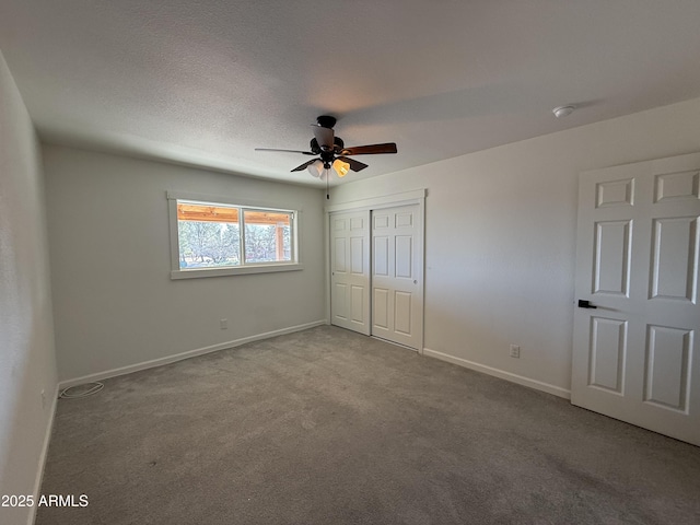 unfurnished bedroom featuring baseboards, carpet floors, a closet, a textured ceiling, and a ceiling fan