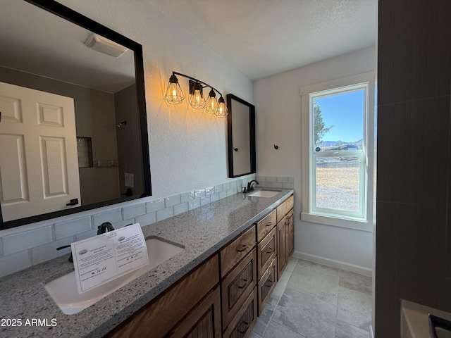 bathroom featuring a sink, decorative backsplash, a healthy amount of sunlight, and double vanity