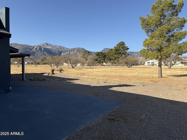 view of yard with a rural view, a mountain view, and fence