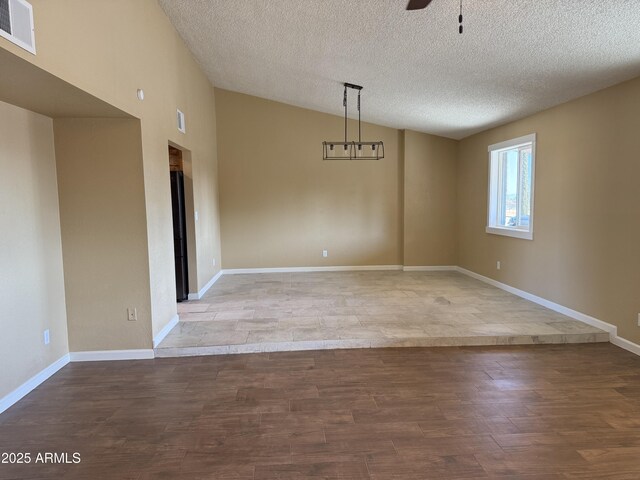unfurnished dining area with wood finished floors, visible vents, lofted ceiling, ceiling fan, and a textured ceiling
