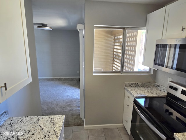 815 N Hayden Rd Unit A205, Scottsdale, AZ 85257 - kitchen featuring stainless steel appliances, white cabinets, light carpet, light stone counters, and light tile patterned floors