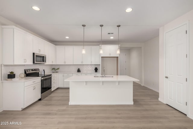 kitchen with white cabinets, light wood finished floors, appliances with stainless steel finishes, and a sink