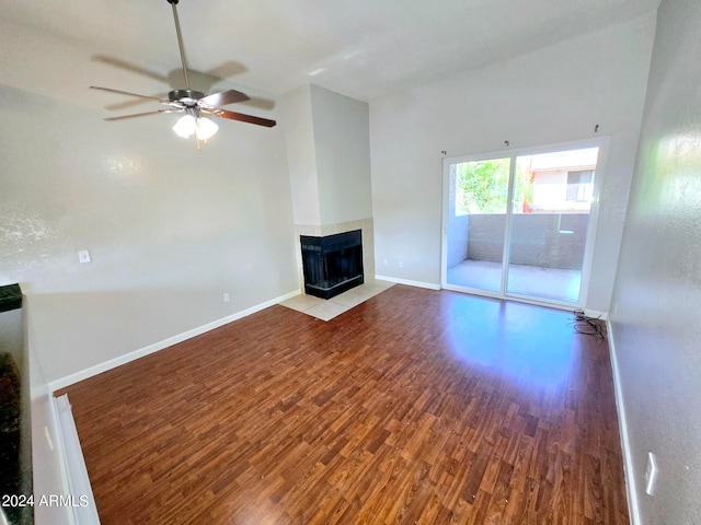 unfurnished living room with ceiling fan, high vaulted ceiling, a multi sided fireplace, and wood-type flooring